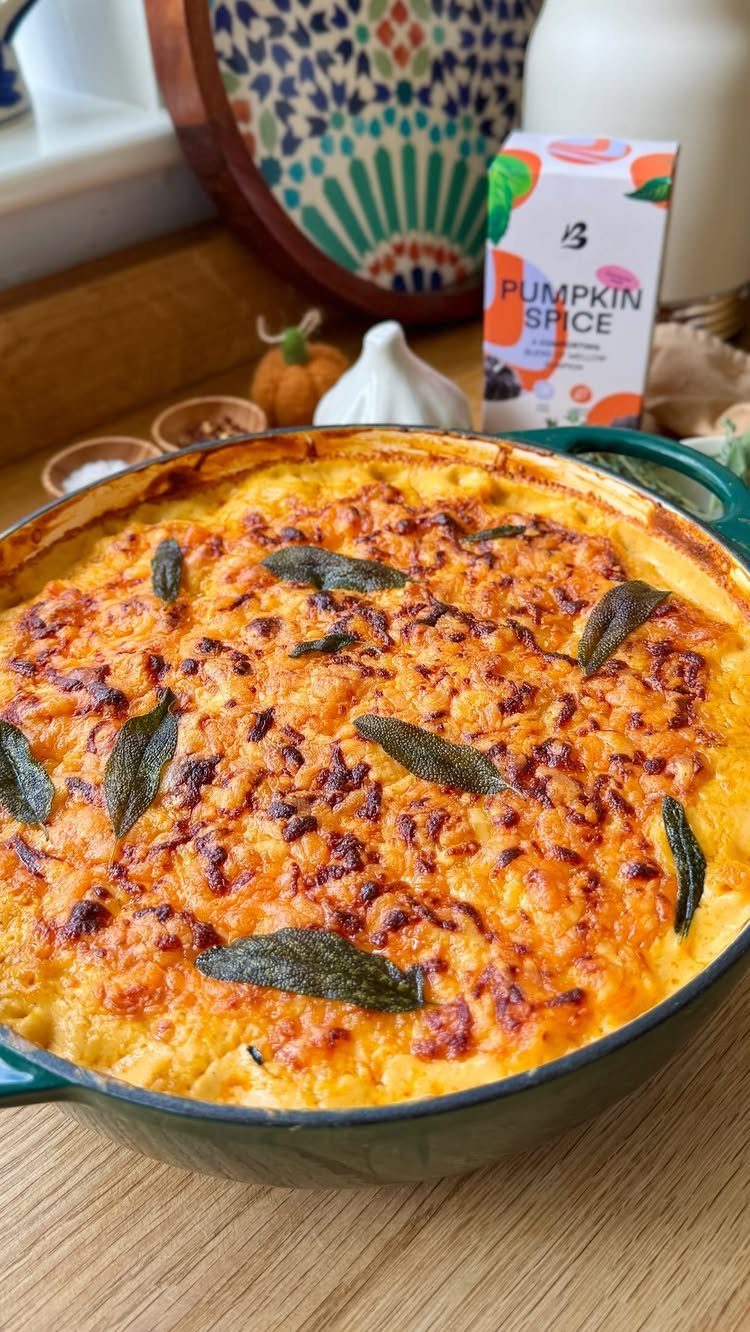 Baked macaroni and cheese with a browned cheese crust and sage leaves in dish.