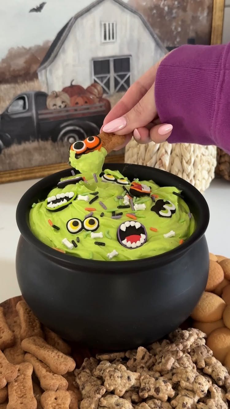 Green monster dip in a black cauldron surrounded by bone-shaped crackers.
