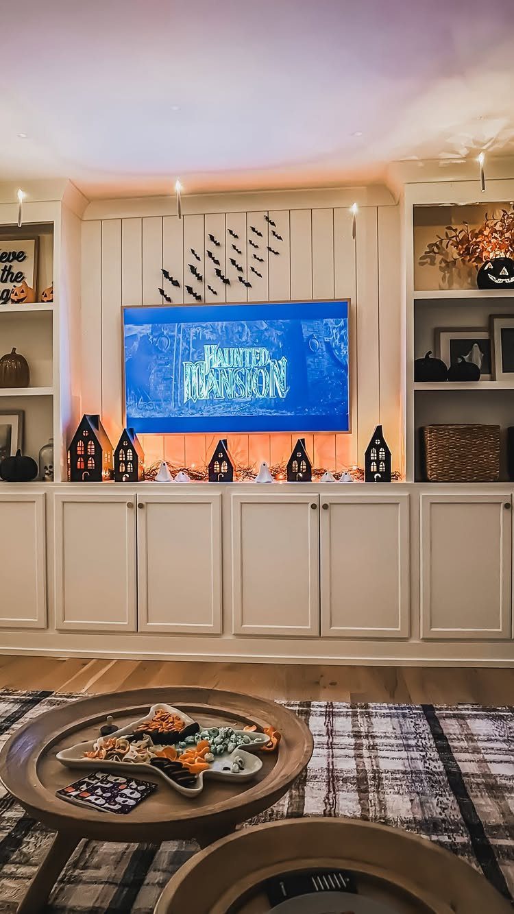 Living room decorated for Halloween with a horror movie playing on the television.