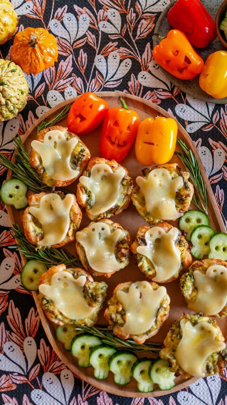 Spinach and artichoke dip on toast with ghost-shaped melted cheese and vegetables.