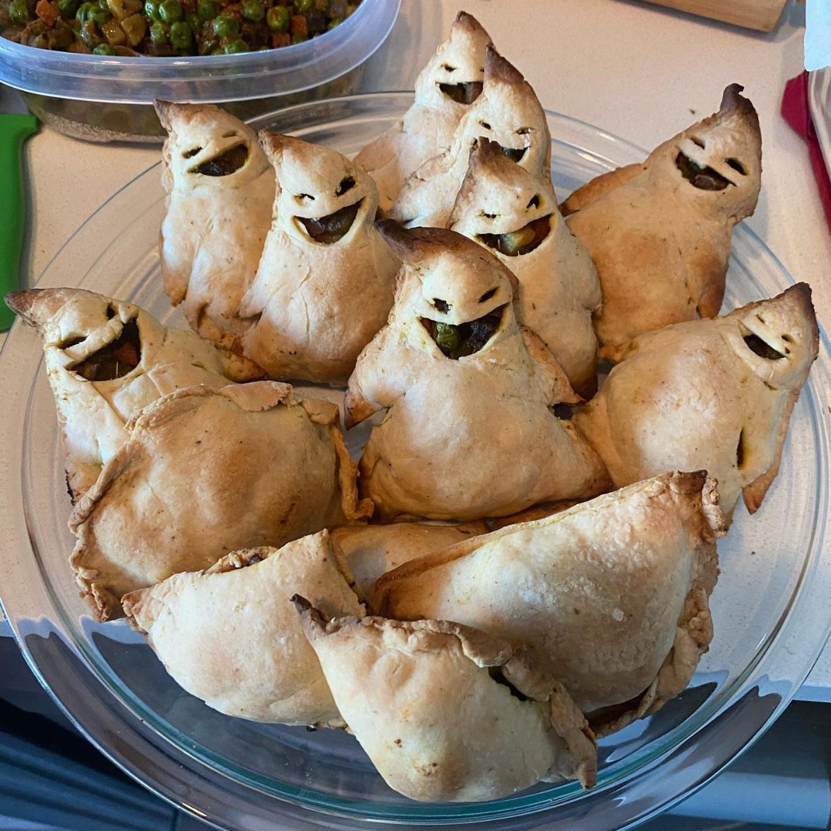 Ghost shaped pastry pockets with olive smiles in a clear glass bowl.