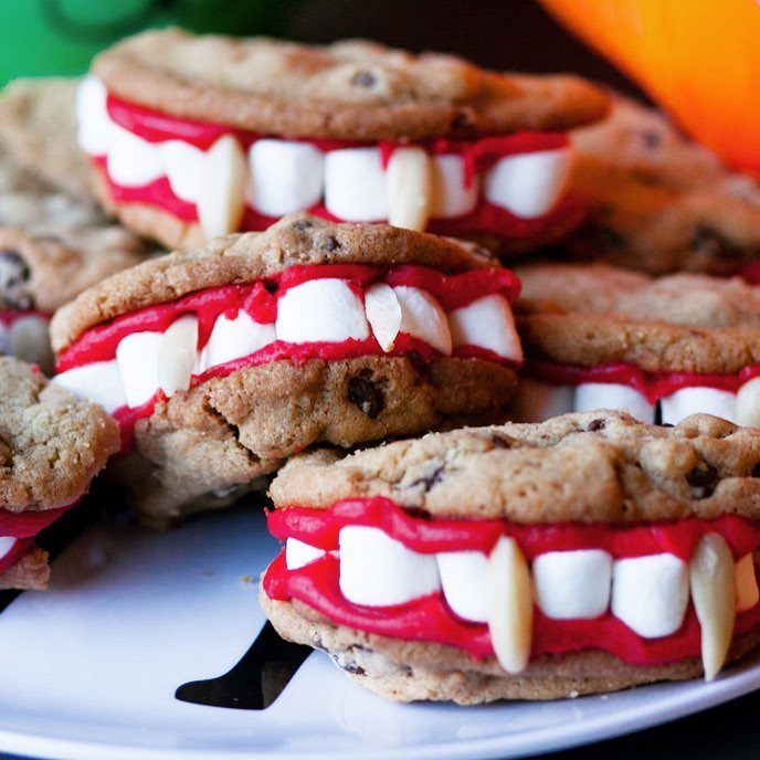 Chocolate chip cookie sandwiches with red frosting and marshmallow teeth like vampire dentures.