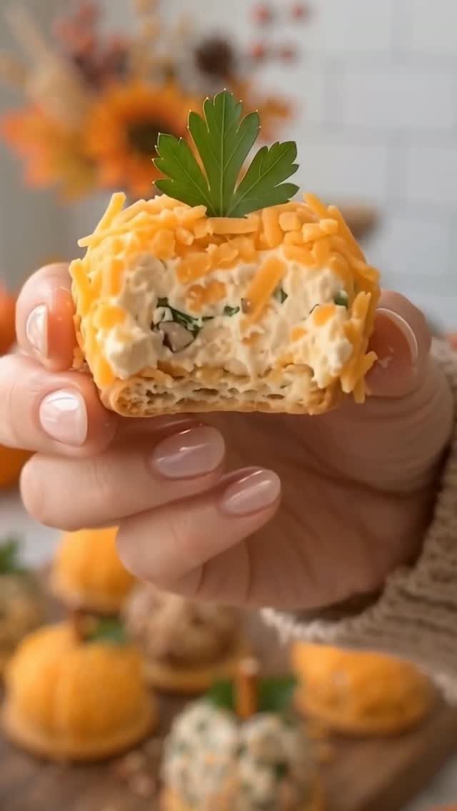 Pumpkin-shaped cheese ball with shredded orange cheese and a parsley stem topper.