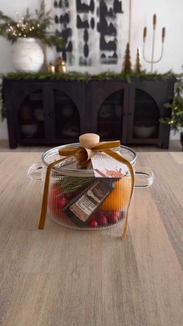 Glass gift bowl filled with fruit and treats tied with gold ribbon