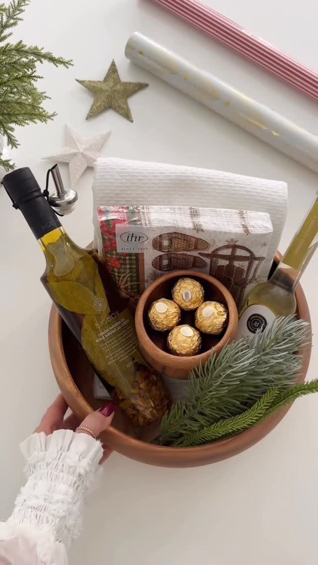 Terracotta gift bowl with olive oil, chocolates, and a white dish towel.