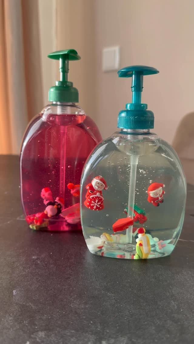 Two soap dispensers with pink and clear liquid containing small holiday figurines.