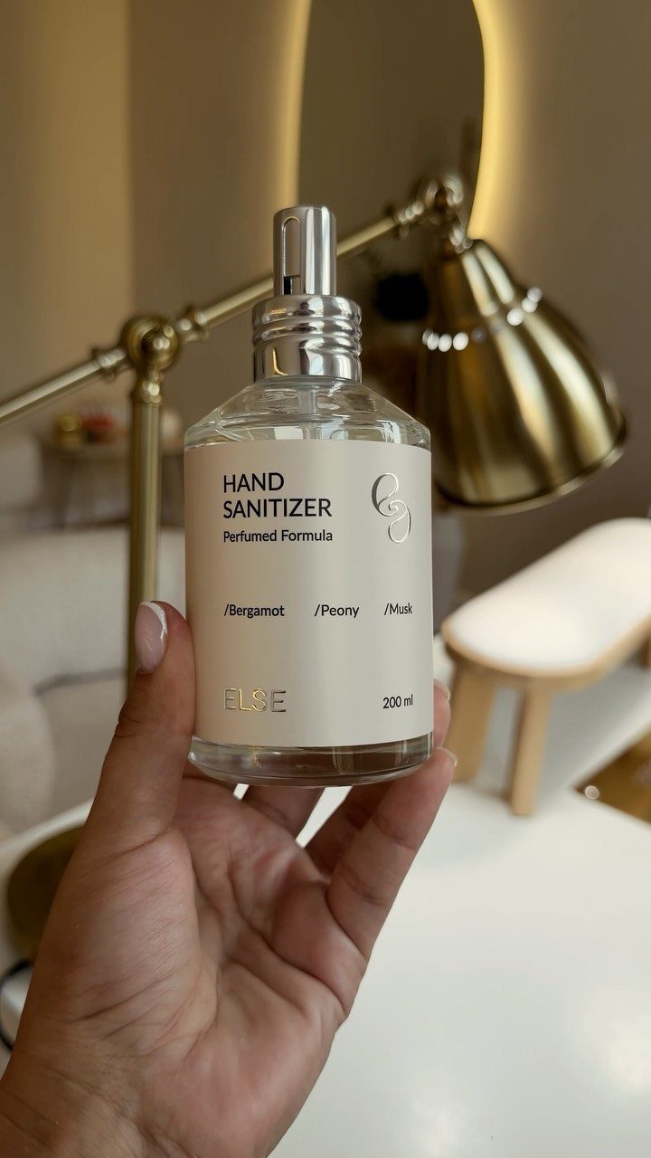 Hand sanitizer in a clear glass bottle with a silver pump and white label.