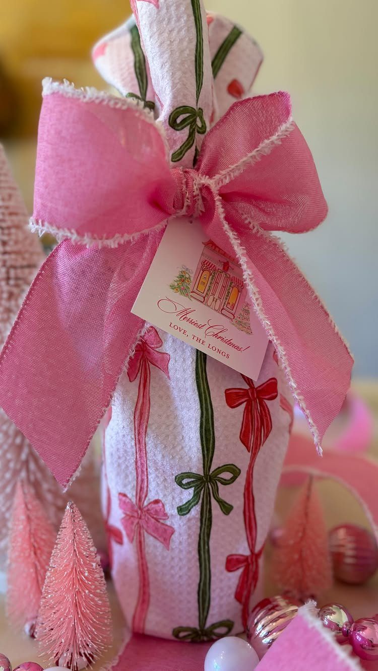 Wrapped wine bottle with pink bow and Christmas tag among pink decorations