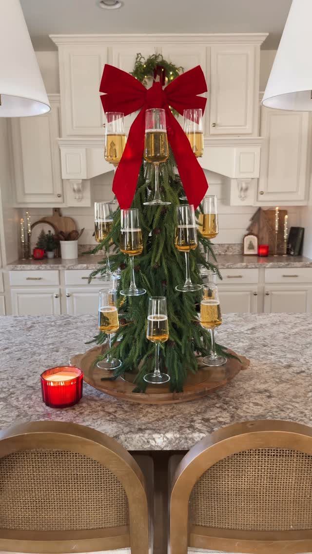 Champagne glass tree with a red bow on a granite kitchen counter.