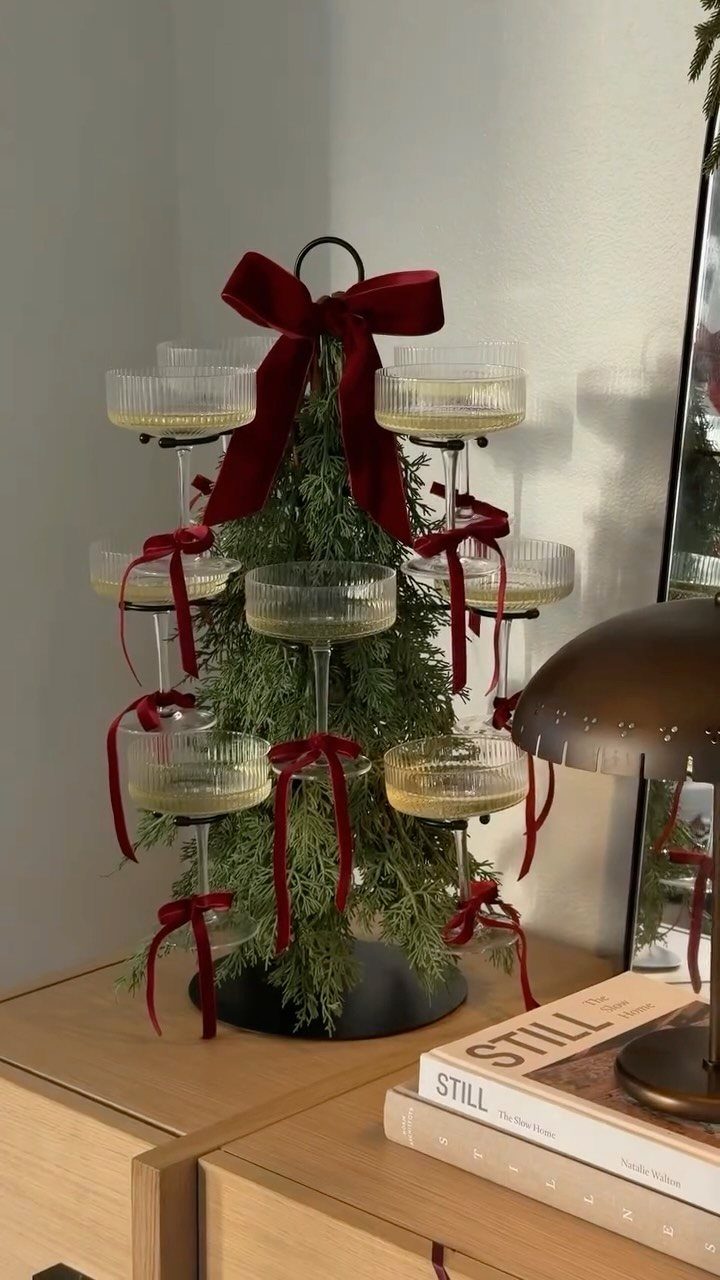 Champagne glass tower decorated with red ribbons around a small evergreen tree.