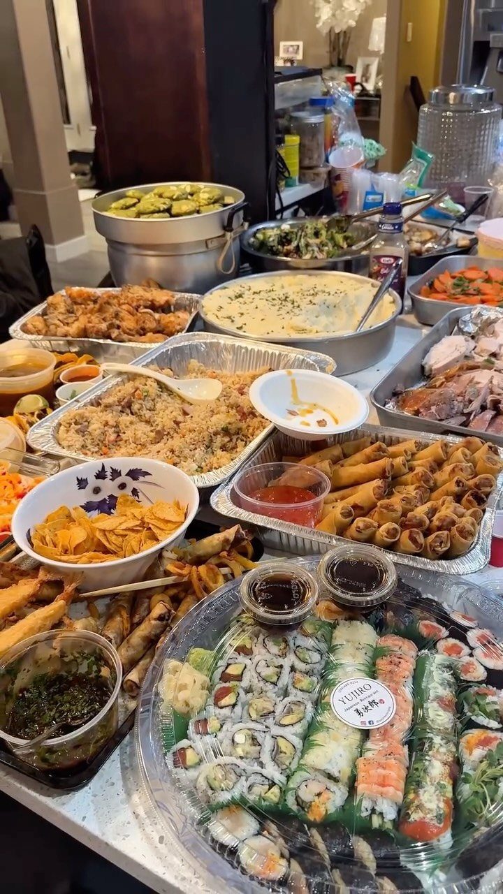 Assorted party foods including sushi, spring rolls, and fried chicken on a table.