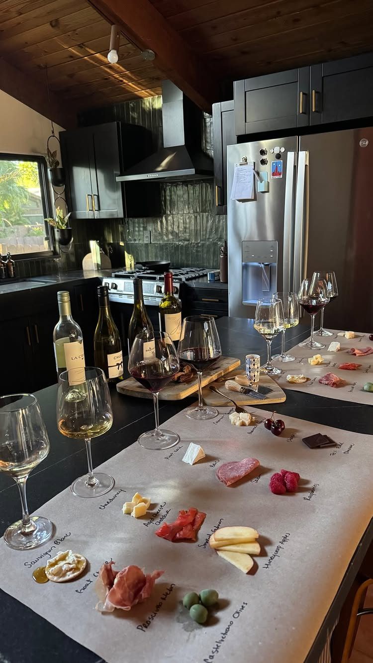 Charcuterie board with cheeses and meats paired with red and white wine glasses.