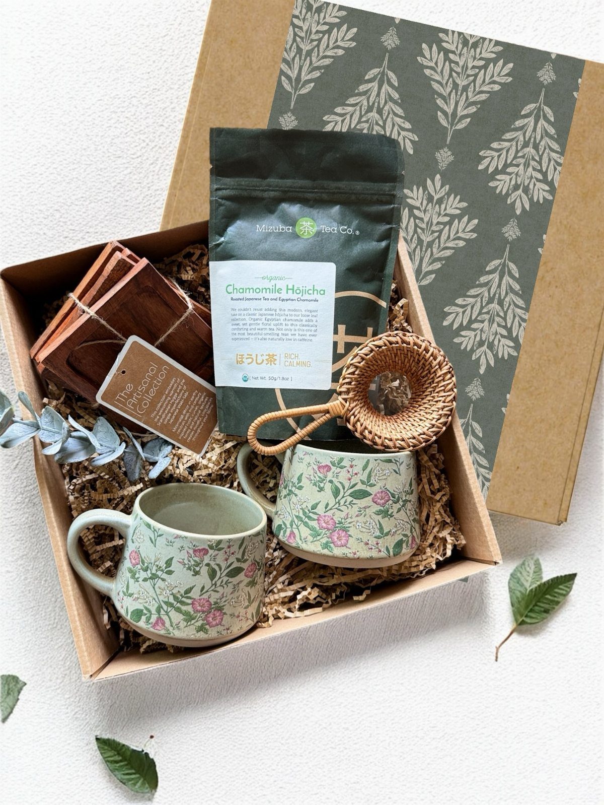 Two floral mugs and a bag of tea in a gift box