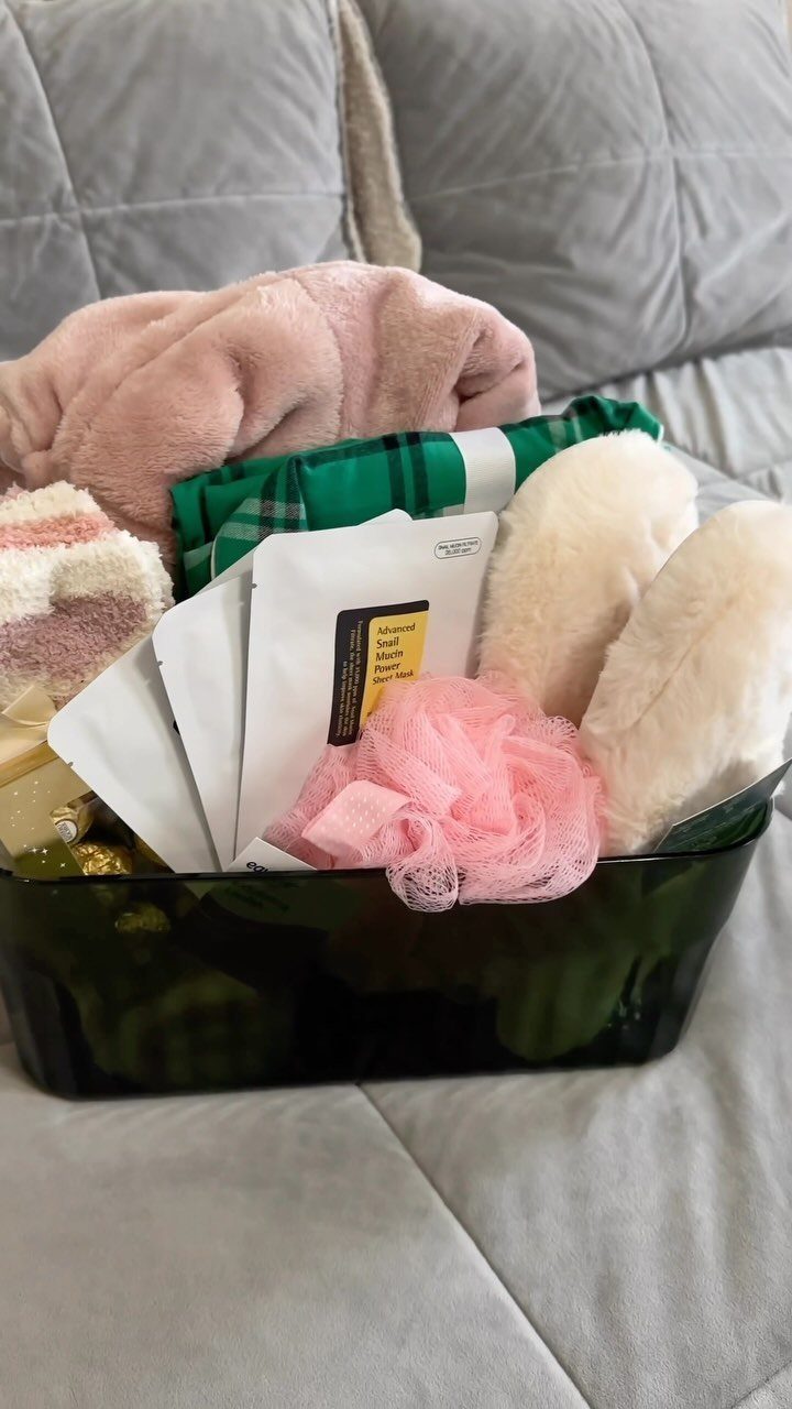 Welcome basket with pink blanket, white slippers, and bath accessories on a sofa