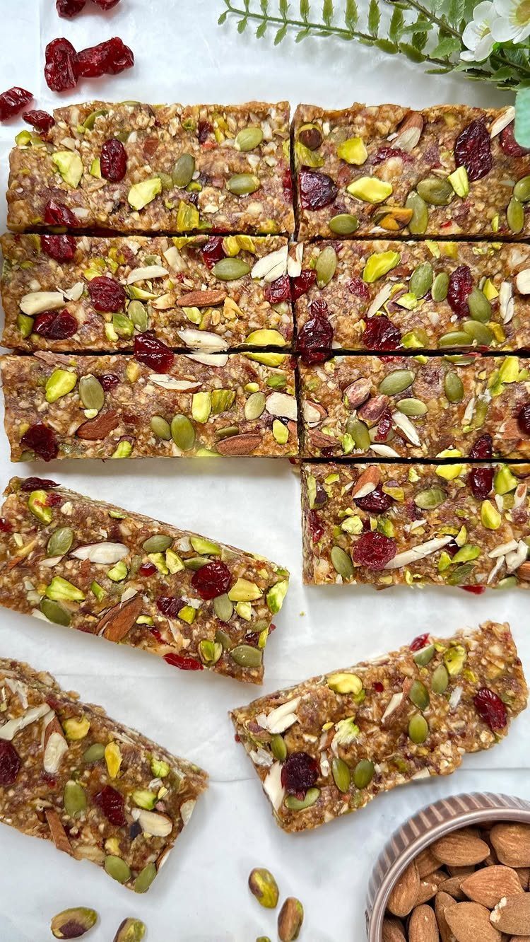 Granola bars with nuts and dried cranberries on white parchment paper.