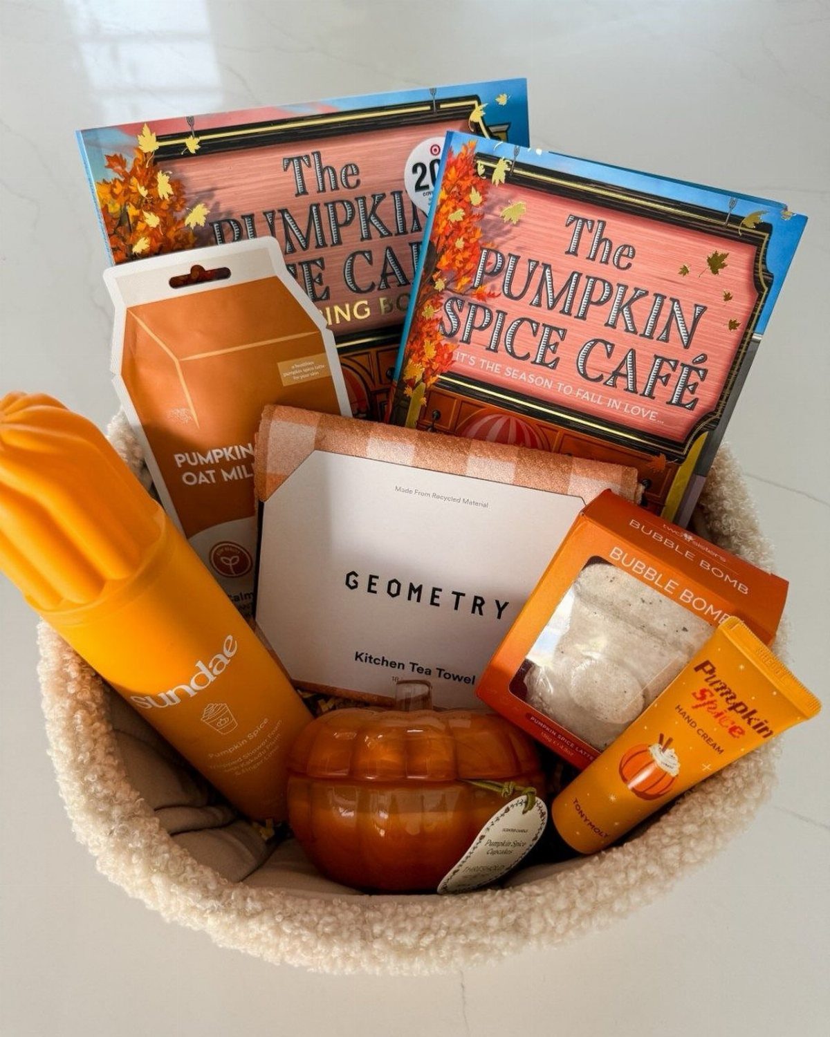 Autumn-themed welcome basket with pumpkin spice treats, a candle, and a tea towel.