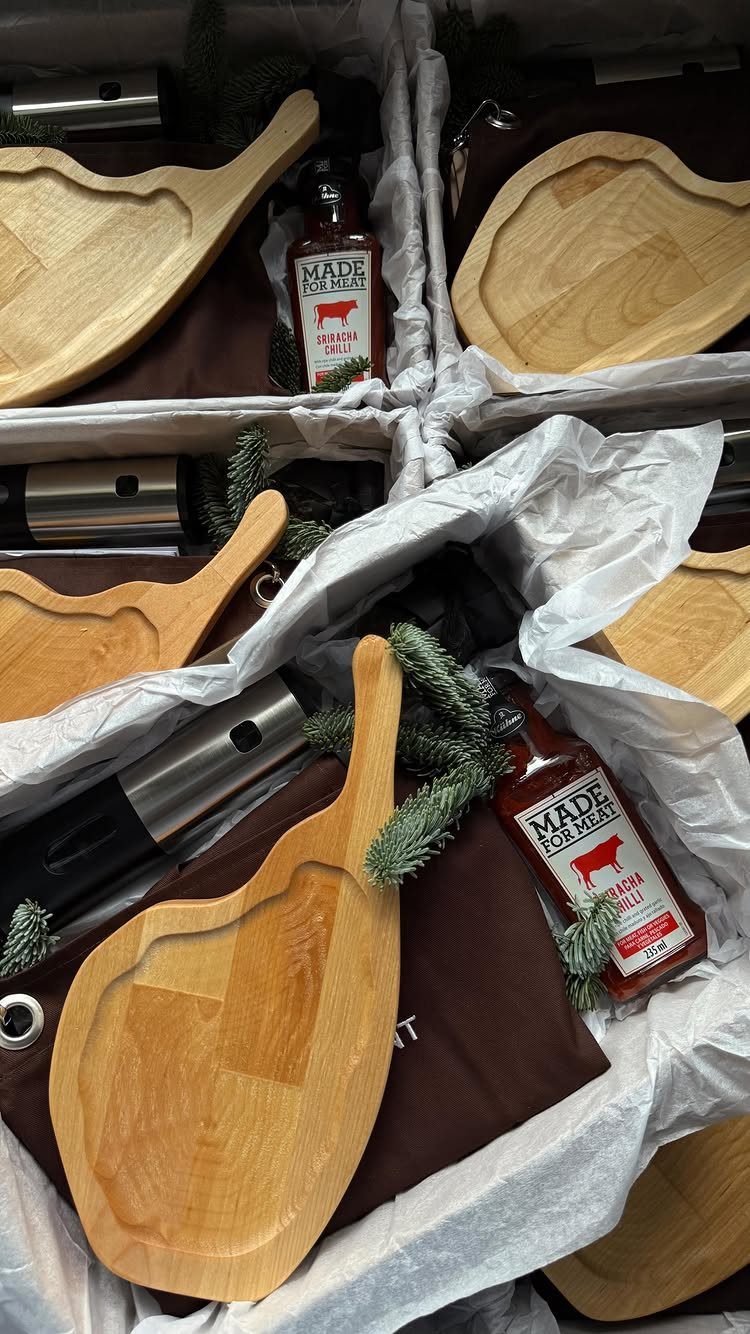 Gift baskets with wooden serving boards, meat sauce, and kitchen tools for housewarming.