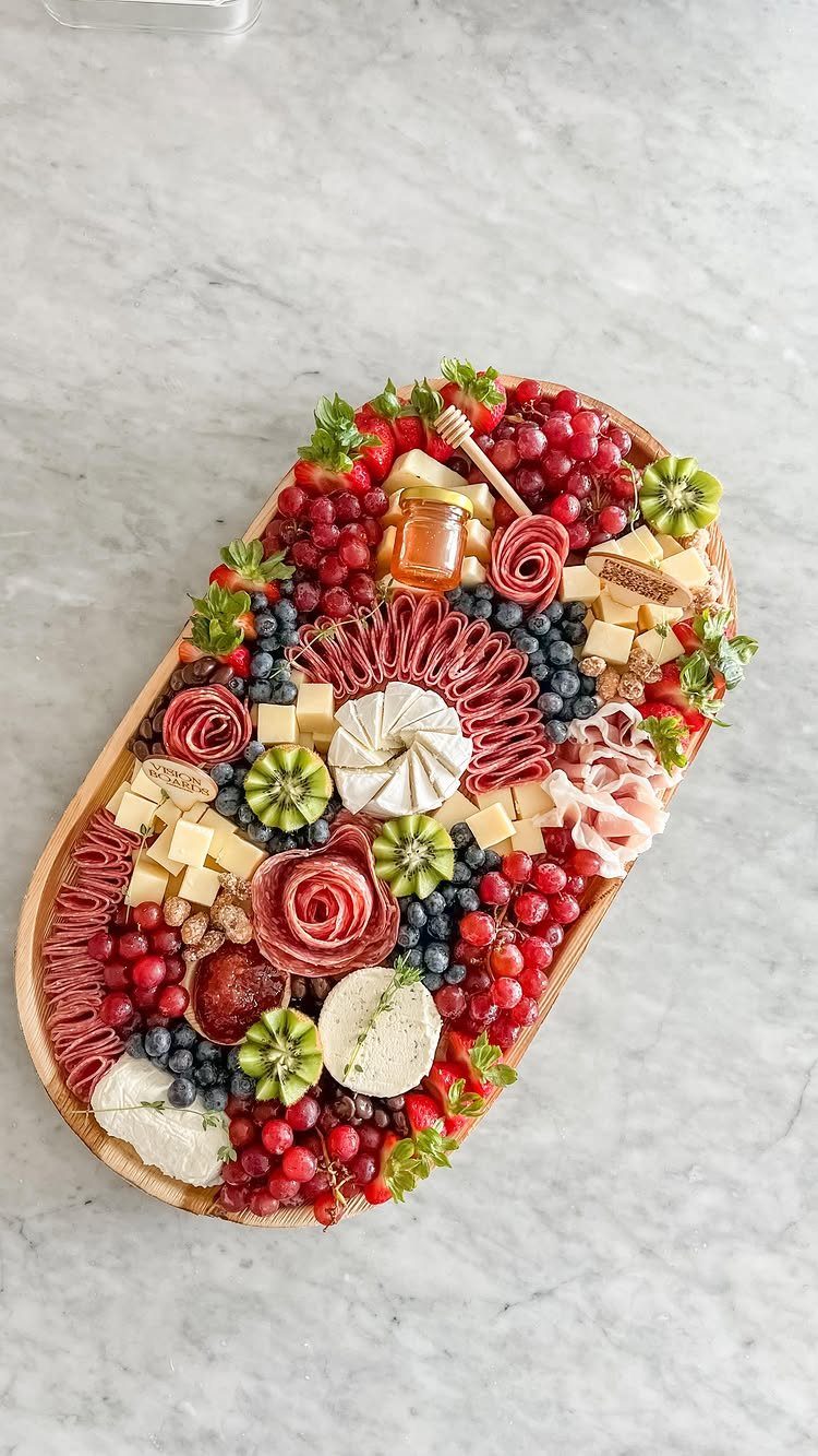 Wine bottle shaped charcuterie board with meats, cheeses, and fresh fruits on marble.
