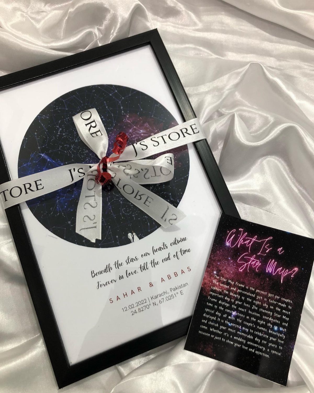 Framed personalized star map with a white ribbon on white satin fabric.
