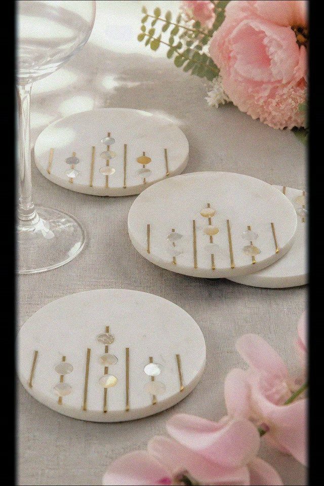 White marble coasters with gold metallic inlays next to a wine glass and flowers