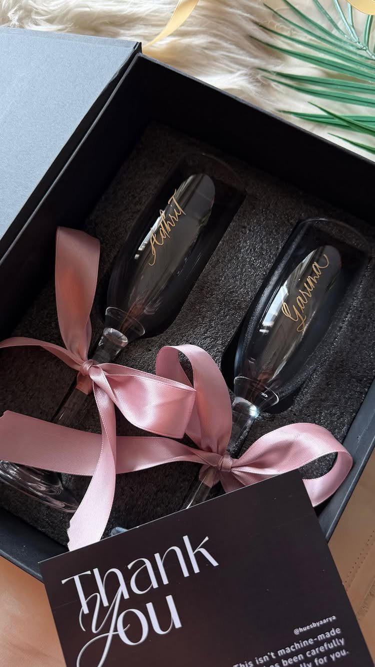 Personalized champagne flutes in a black gift box with pink ribbons and thank you card