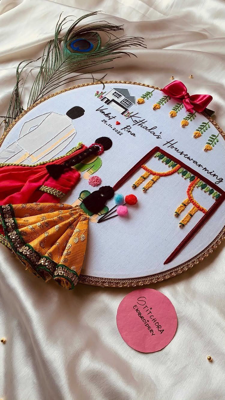 Circular housewarming plaque with 3D fabric couple and house illustration on white satin.