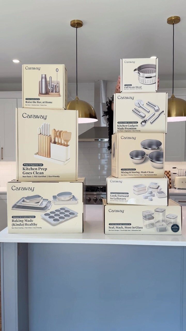Stacked Caraway kitchenware gift boxes on a white counter in a modern kitchen.