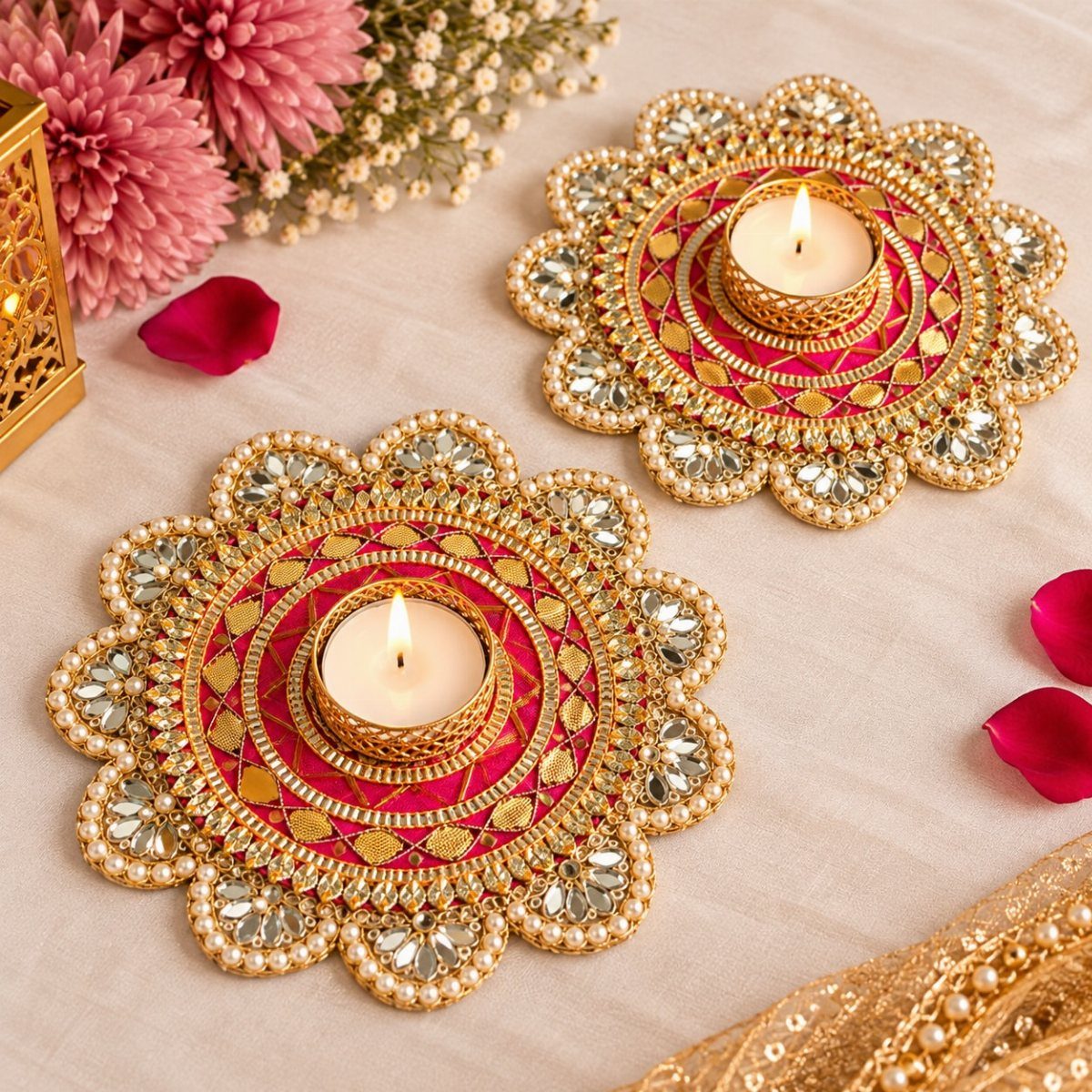 Two ornate gold and pink candle holders with mirrors and lit tea lights.
