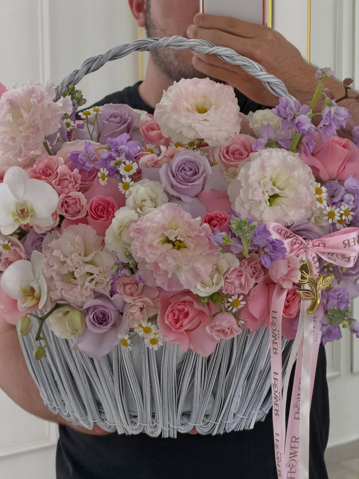 Large grey woven basket filled with pink, purple, and white floral arrangement.