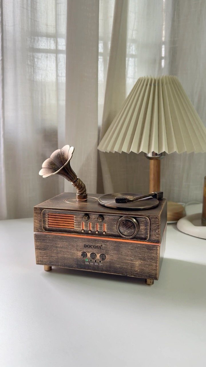 Vintage wooden record player with gold horn next to a pleated cream lamp