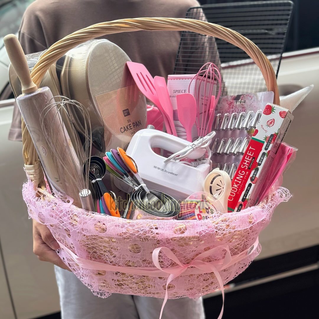 Baking kit in a pink lace basket with mixer, whisks, and spatulas.