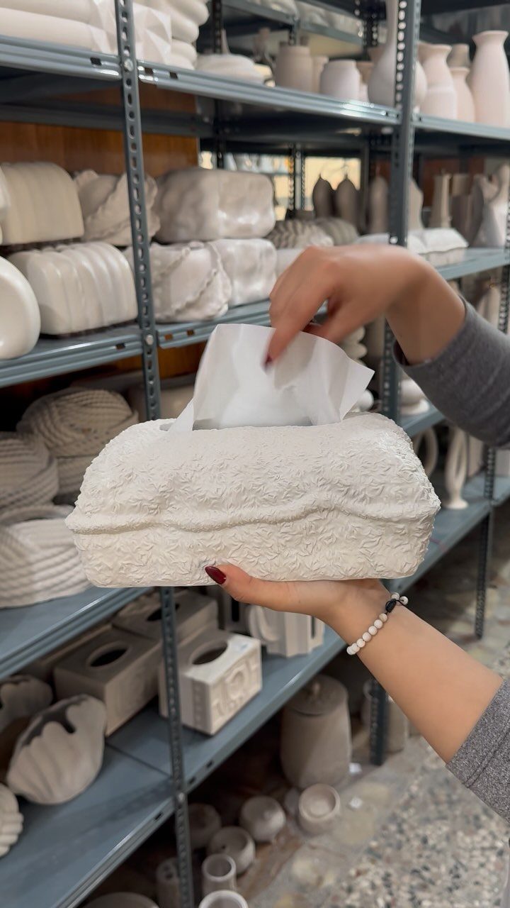 White textured ceramic tissue box cover held by hands in a pottery studio.
