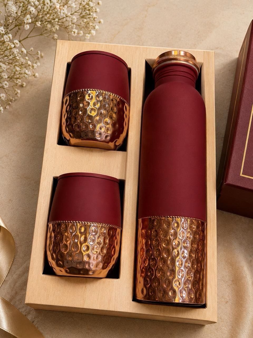 Burgundy and hammered copper drinkware set in a light wooden gift box.