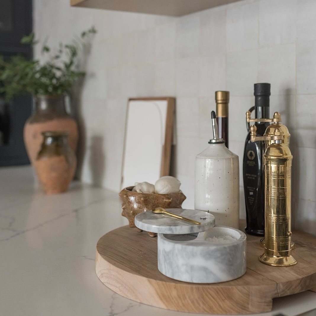 Marble salt cellar with gold spoon on a wooden board in a kitchen