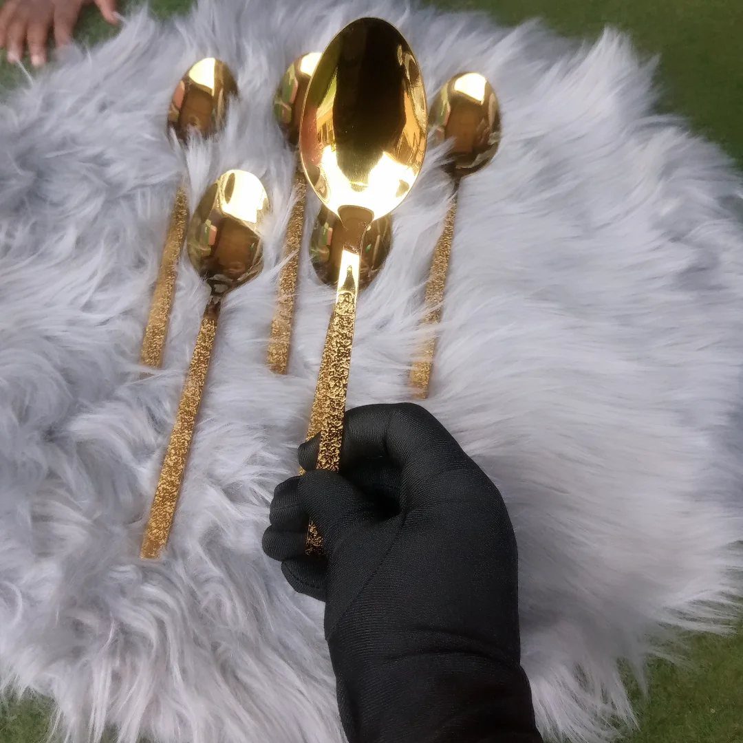 Gold spoons with glittery handles resting on a white faux-fur rug.