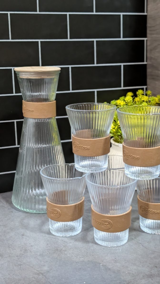 Ribbed glass tumblers with brown bands and a matching carafe on a countertop.