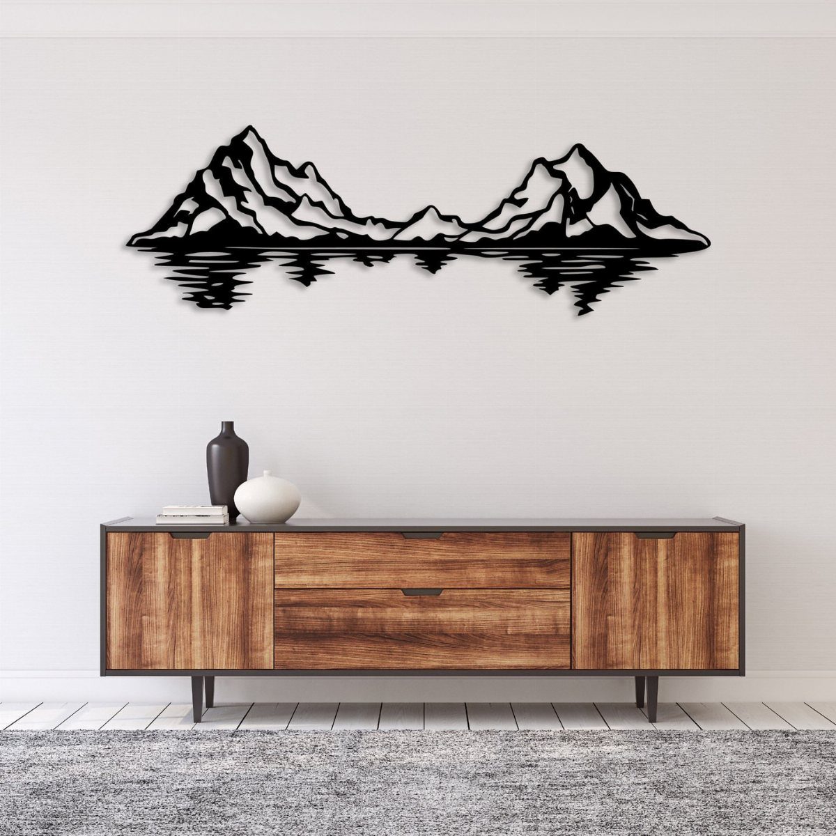 Black metal mountain wall art hanging above a wooden mid-century modern sideboard.