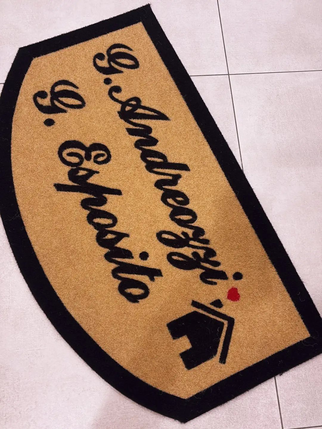 Semi-circular tan welcome mat with personalized black cursive names and a house icon.