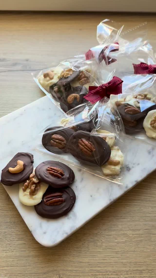 Chocolate nut discs on a marble slab and in clear gift bags.