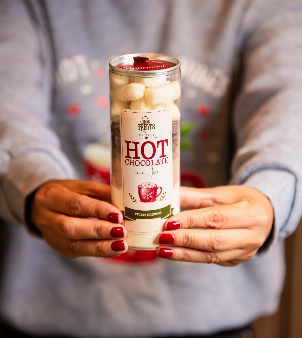 Hot chocolate kit in a glass jar held by a person's hands.
