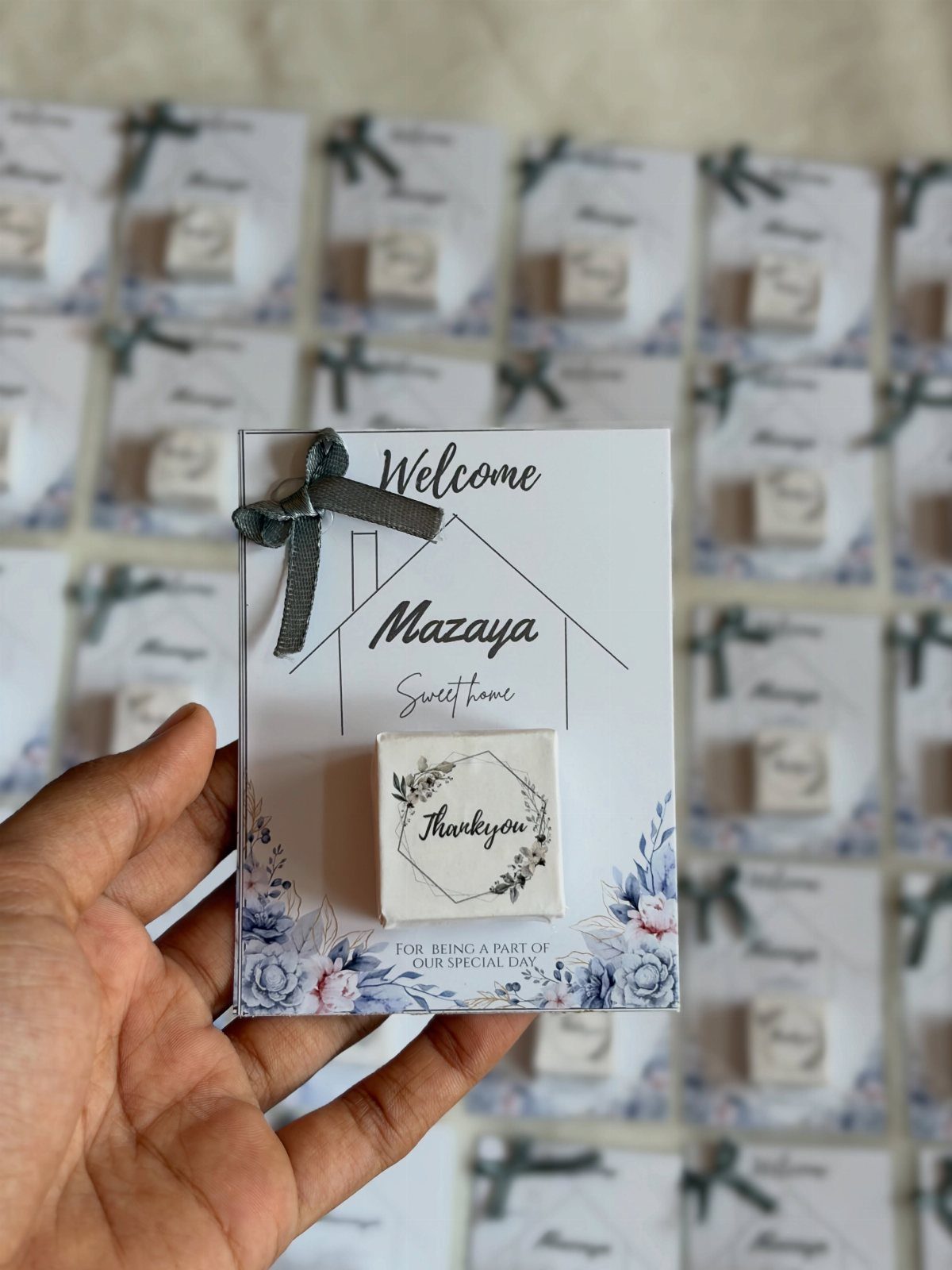 Hand holding a housewarming favor card with a small white soap bar attached.