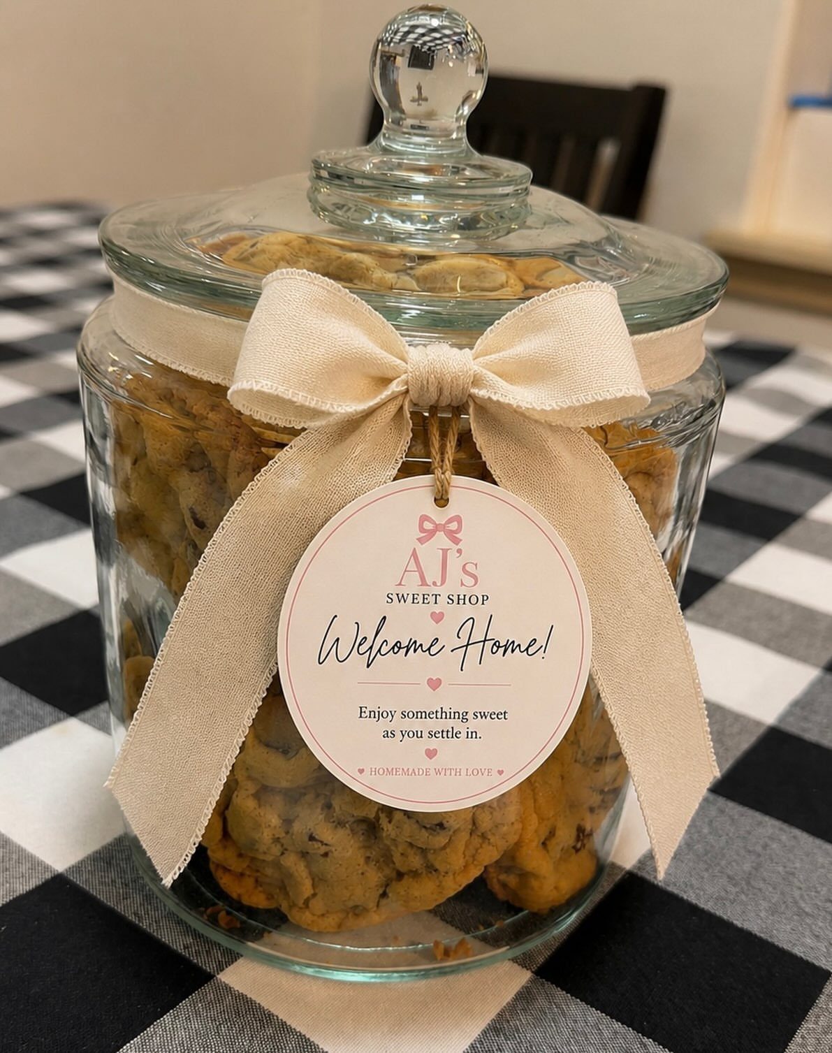 Glass jar of chocolate chip cookies with a welcome home gift tag.