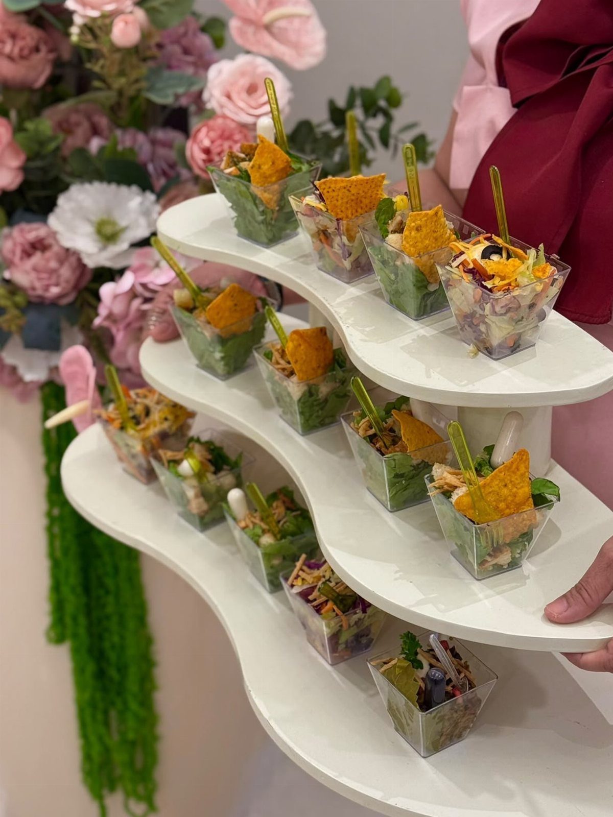 Layered salad bites with tortilla chips on a white tiered serving stand