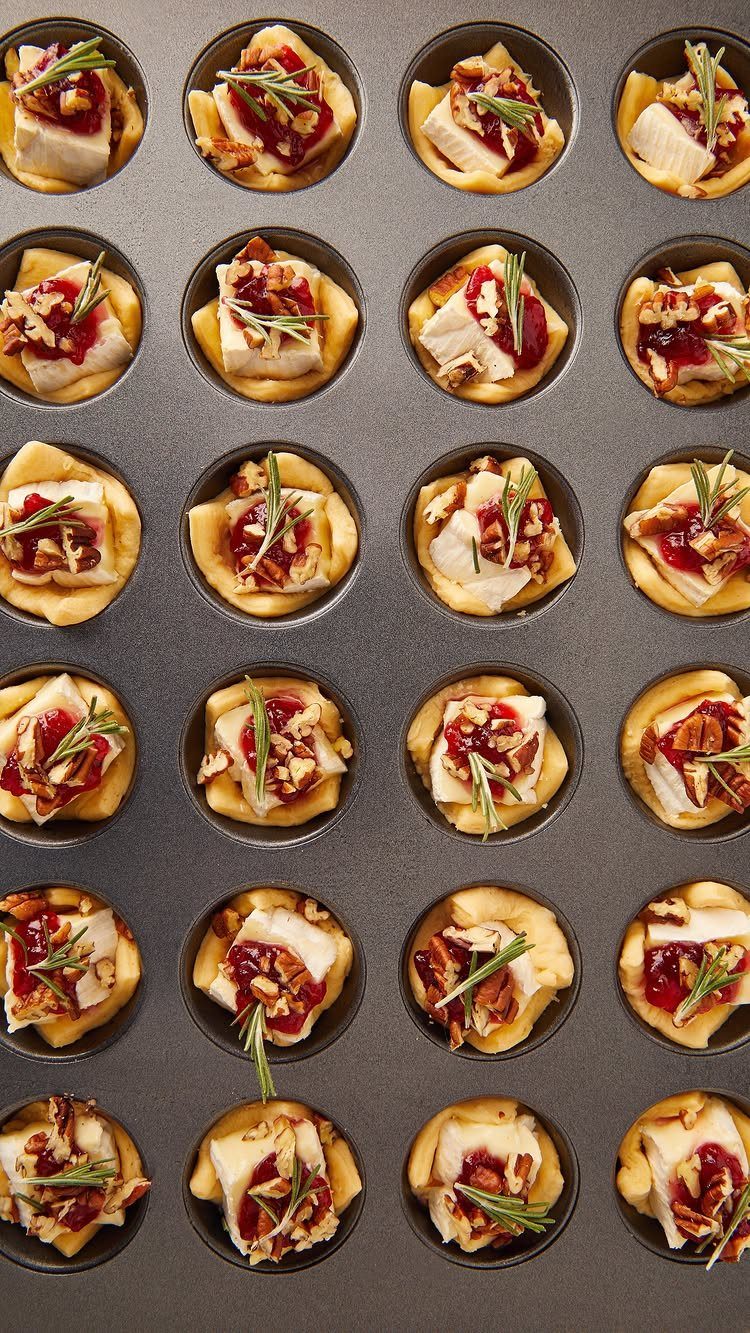 Mini pastry cups with melted brie cheese, cranberry chutney, nuts, and rosemary sprigs.