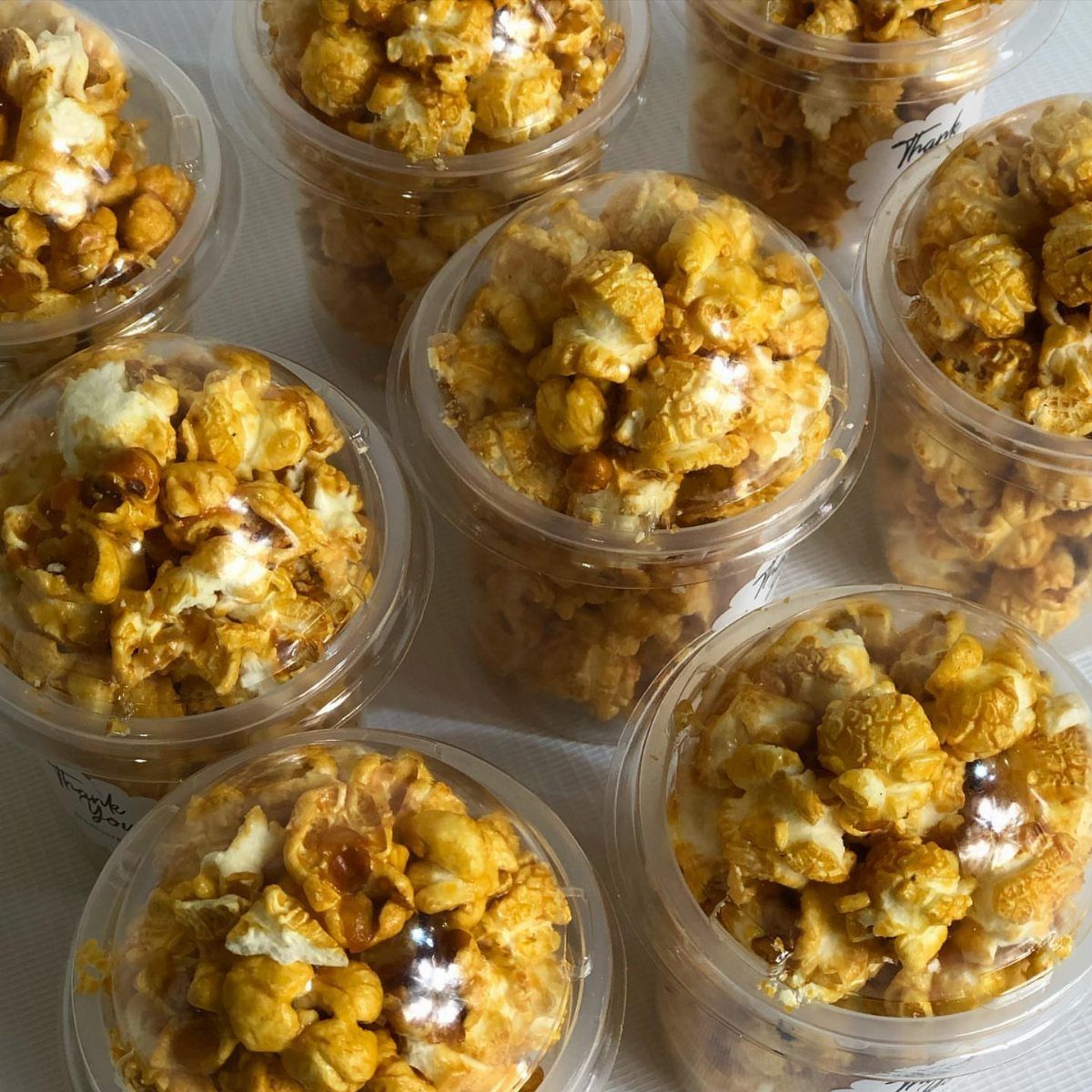 Caramel popcorn in clear plastic containers arranged on a white background.