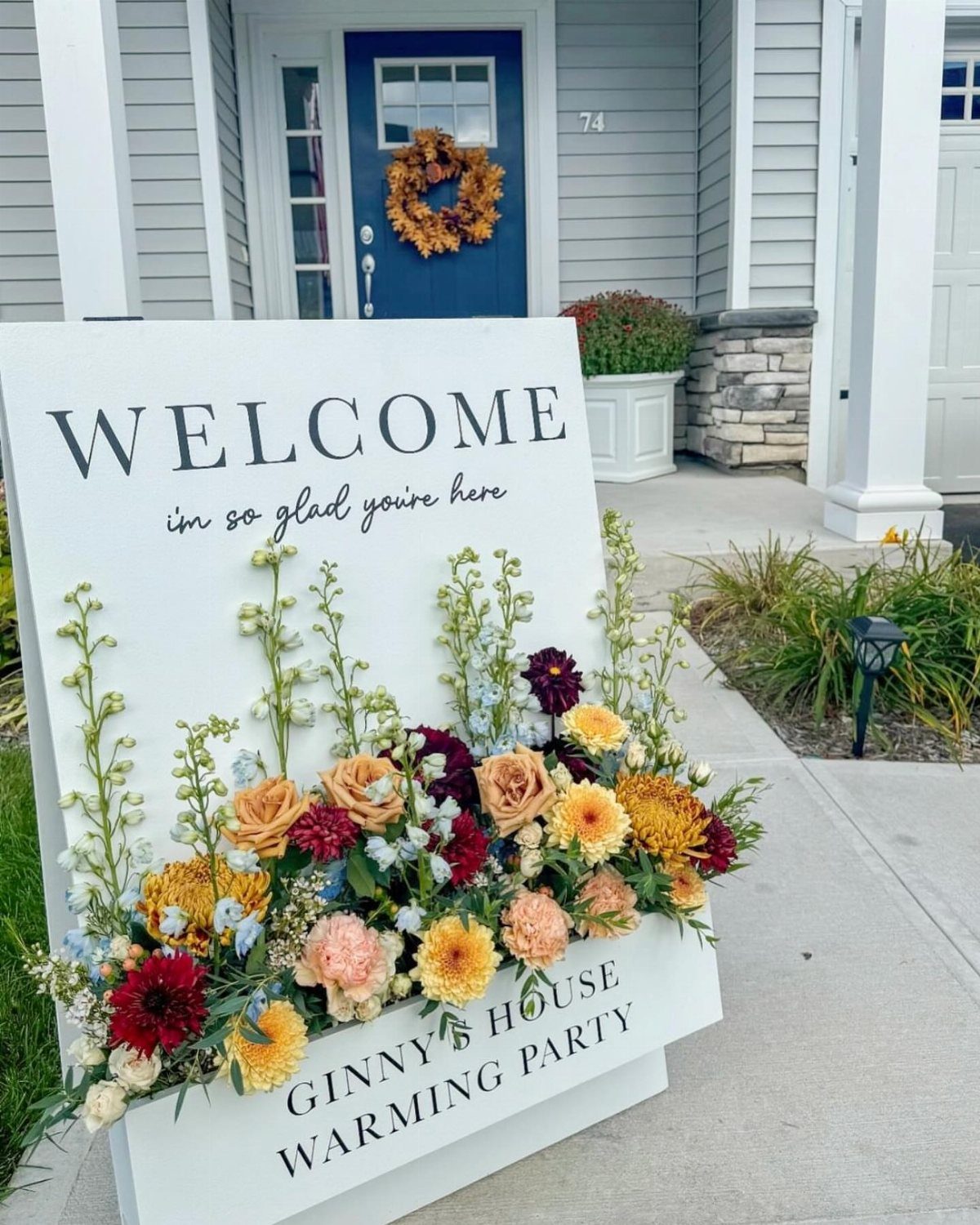 Welcome sign with colorful flowers for a housewarming party in front of a home.