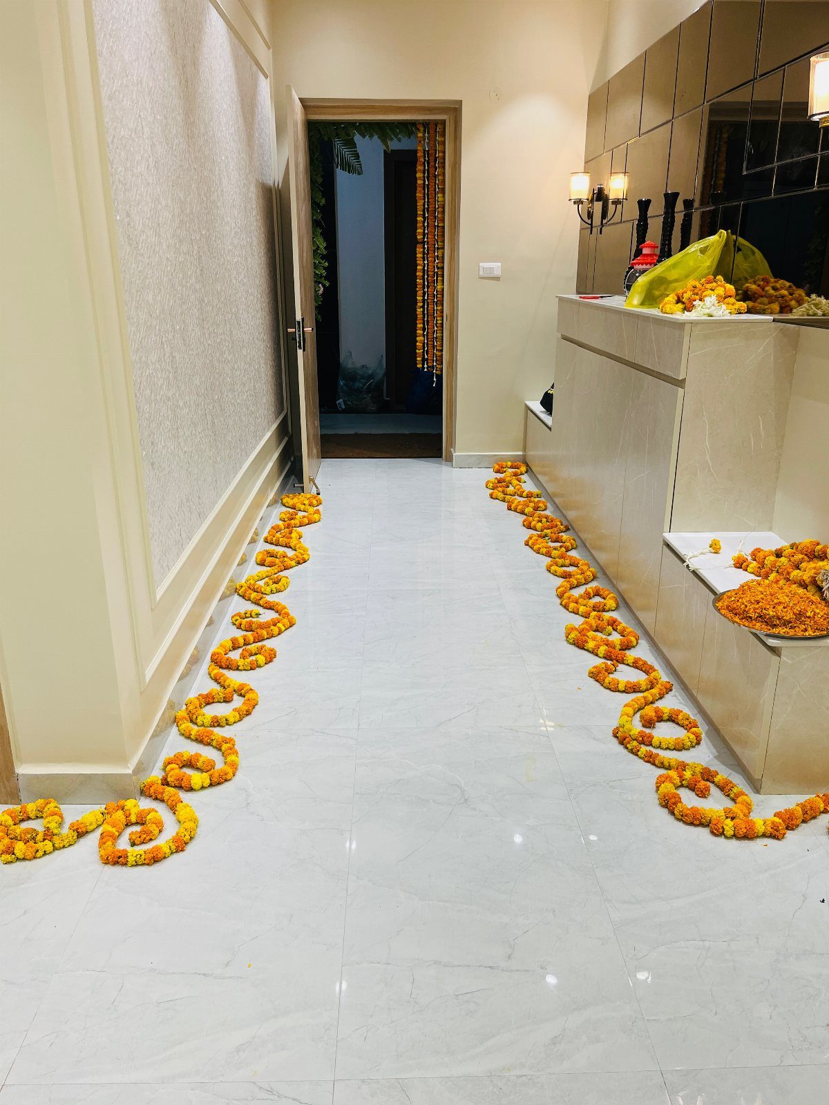 Orange and yellow marigold flower garlands decorating a white marble hallway floor