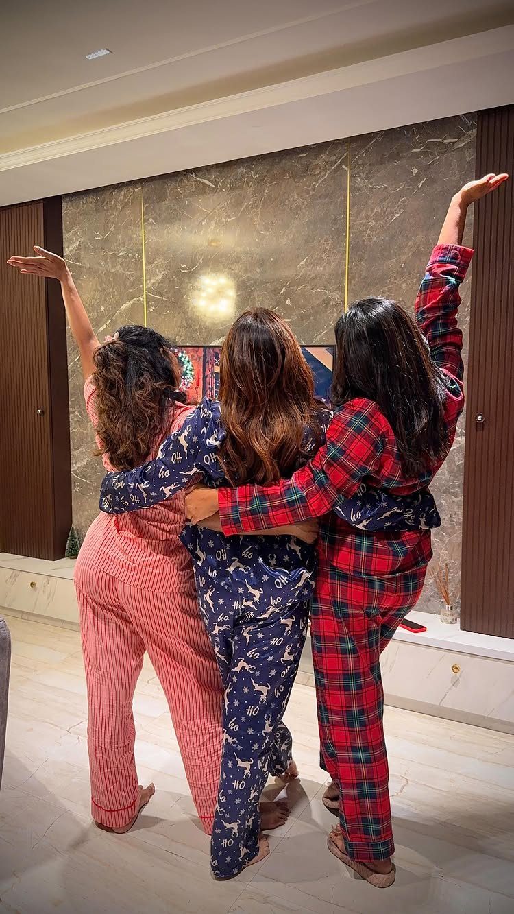 Three women in festive pajamas hugging with their backs to the camera.