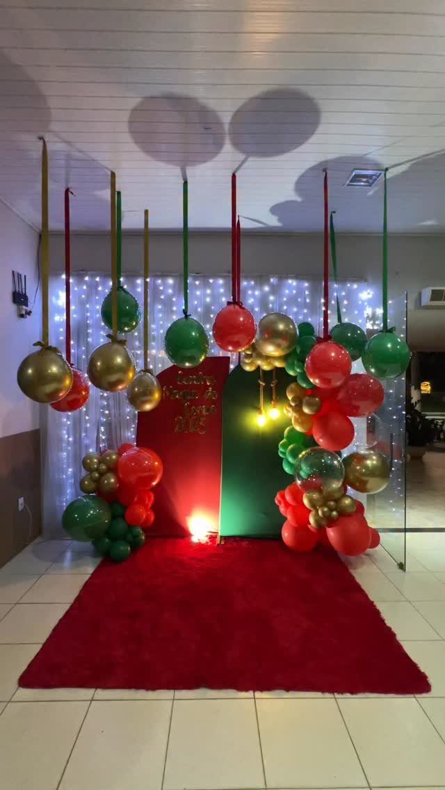Christmas party decorations with red, green, and gold balloons and a red carpet.