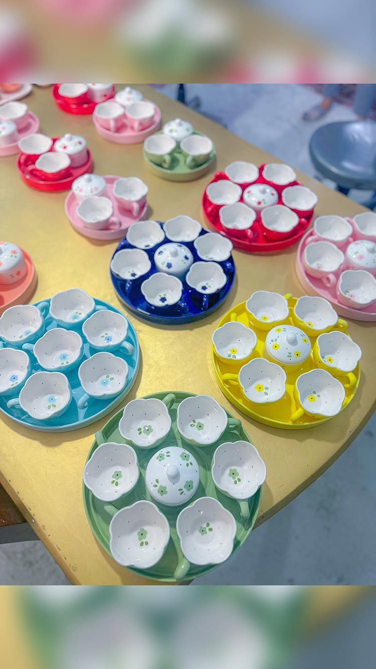 Colorful ceramic condiment sets with flower-shaped bowls on a yellow table.